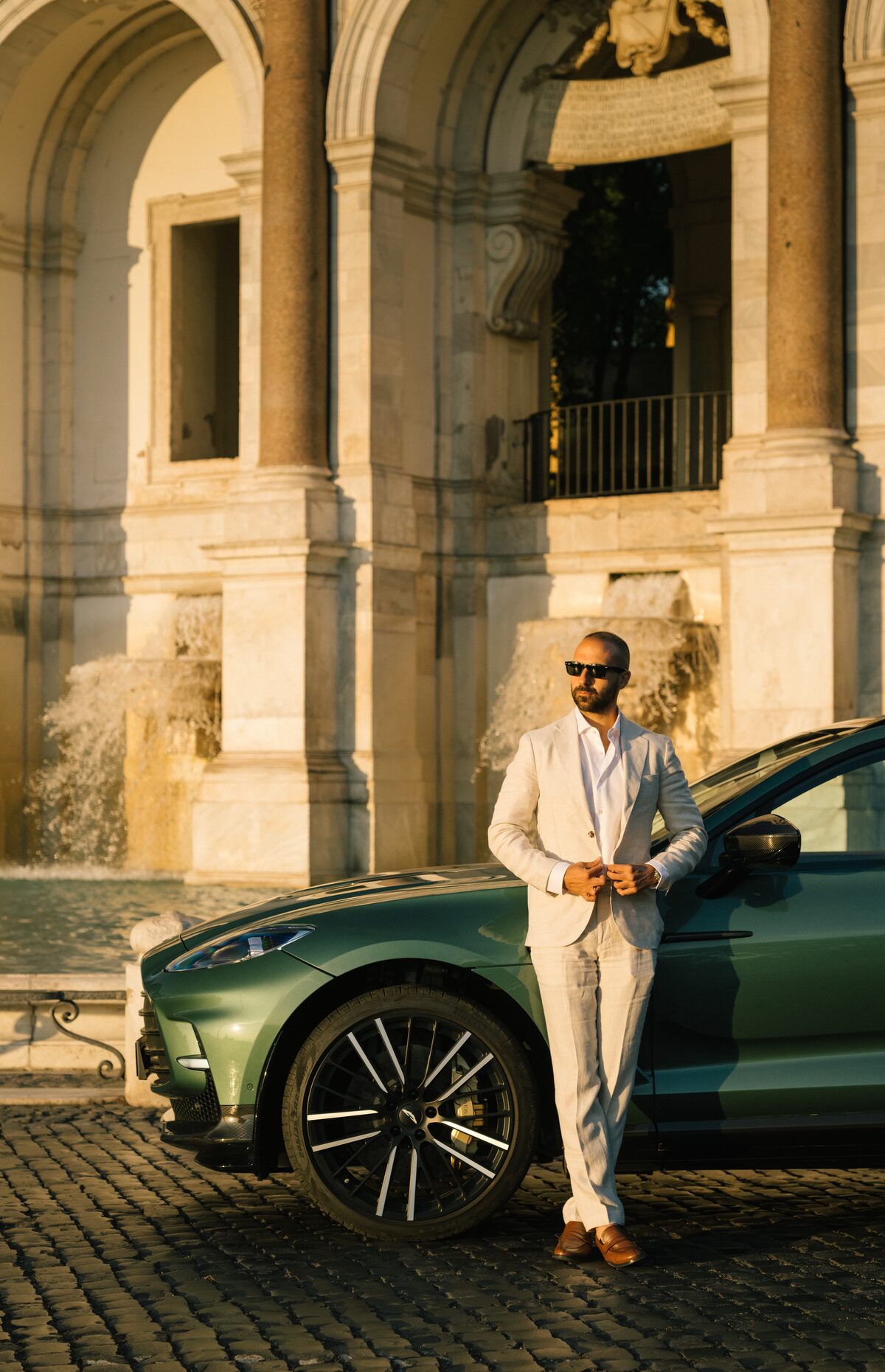 An Aston Martin beneath a Roman arch at dusk