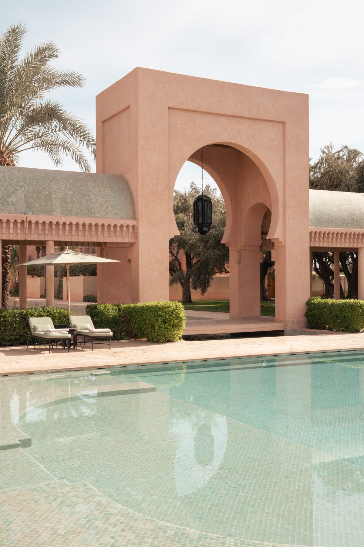 Rose-coloured Moorish arches over a still pool at Amanjena, Marrakech
