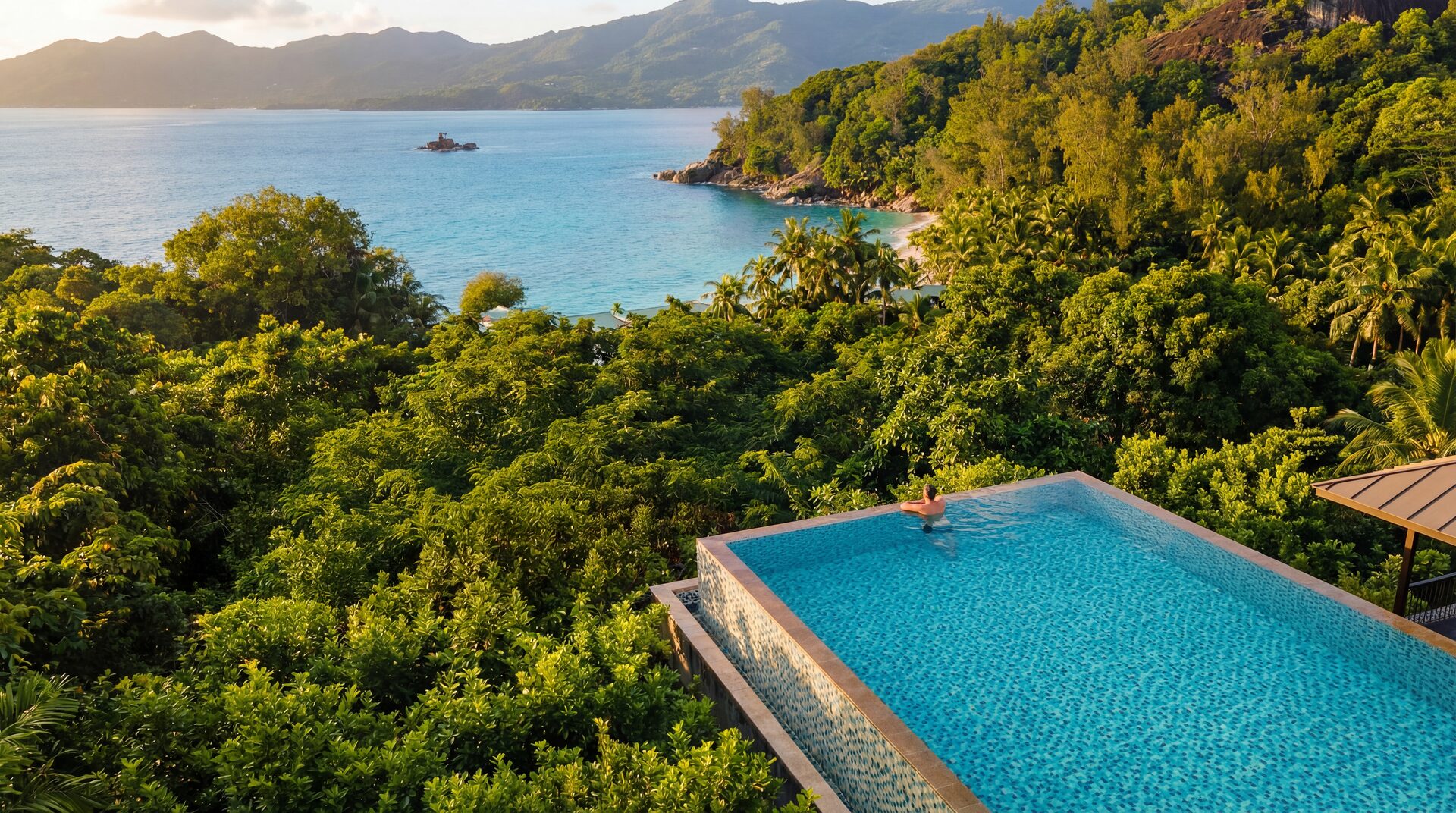 Aerial view of an infinity pool folded into jungle above the Indian Ocean — Four Seasons Seychelles